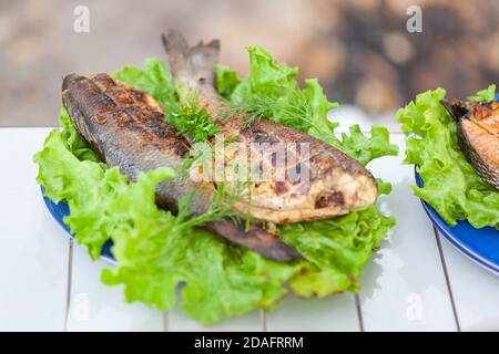bar frit sur une assiette avec des légumes verts Banque D'Images