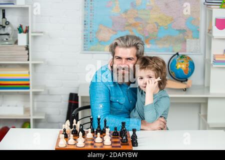 Enfant jouant aux échecs. Enseignant et enfant. Fête des pères. Comme un jeu d'échecs. Papa avec son fils enfant joue aux échecs. Stratégie d'échecs. Banque D'Images