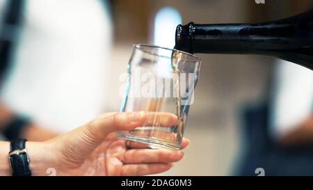 Vue rapprochée et sélective main tenant un verre et une bouteille de vin blanc au goût, dégustation de vins. Banque D'Images