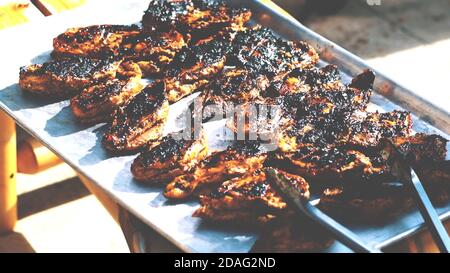 Steak de bœuf trop cuit sur le barbecue, viande grillée brûlée sur une table en acier inoxydable en arrière-plan le jour d'été. Banque D'Images