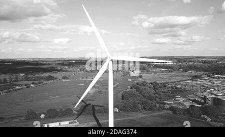 Éolienne, zone industrielle champs agricoles en arrière-plan, production d'énergie propre, vue aérienne en noir et blanc. Banque D'Images