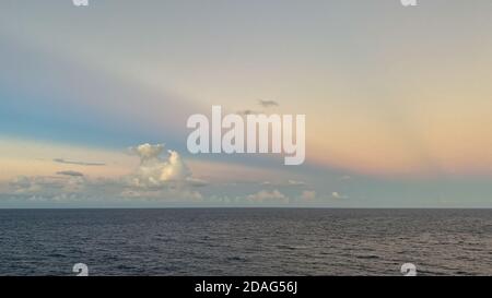 Un beau coucher de soleil rose, bleu et orange sur la mer des caraïbes, le soir d'une nuit brumeuse. Banque D'Images