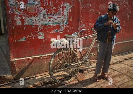 Varanasi, Inde, décembre 2015. Un garçon mange un yaourt dans la rue. Banque D'Images