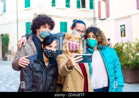 groupe heureux d'amis portant un masque de protection prenant un selfie dans la rue de la ville après le verrouillage rouvrant.hommes multiethniques et une femme Banque D'Images