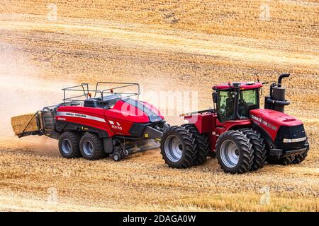 Tracteur à roues 4RM CaseIH tirant une grande presse à balles rectangulaires à Balle de paille de blé dans la région de Palouse, dans l'est de l'État de Washington Banque D'Images