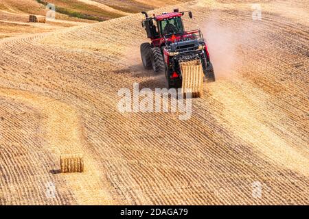 Tracteur à roues 4RM CaseIH tirant une grande presse à balles rectangulaires à Balle de paille de blé dans la région de Palouse, dans l'est de l'État de Washington Banque D'Images