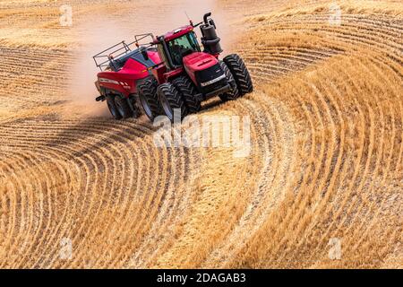 Tracteur à roues 4RM CaseIH tirant une grande presse à balles rectangulaires à Balle de paille de blé dans la région de Palouse, dans l'est de l'État de Washington Banque D'Images