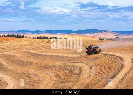 Tracteur à roues 4RM CaseIH tirant une grande presse à balles rectangulaires à Balle de paille de blé dans la région de Palouse, dans l'est de l'État de Washington Banque D'Images