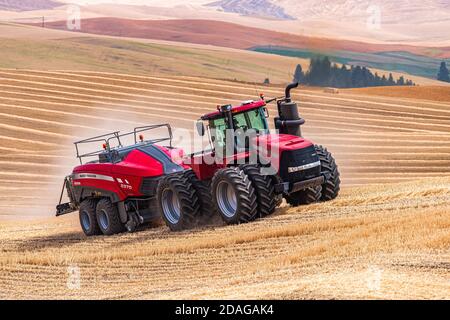 Tracteur à roues 4RM CaseIH tirant une grande presse à balles rectangulaires à Balle de paille de blé dans la région de Palouse, dans l'est de l'État de Washington Banque D'Images