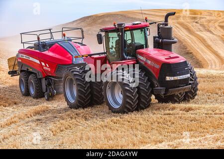 Tracteur à roues 4RM CaseIH tirant une grande presse à balles rectangulaires à Balle de paille de blé dans la région de Palouse, dans l'est de l'État de Washington Banque D'Images