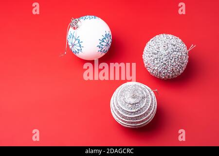 Composition du nouvel an de Noël. Cadeaux, boules argentées et blanches sur fond rouge. Concept vacances d'hiver. Vue en angle Banque D'Images