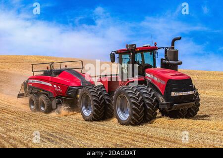 Tracteur à roues 4RM CaseIH tirant une grande presse à balles rectangulaires à Balle de paille de blé dans la région de Palouse, dans l'est de l'État de Washington Banque D'Images