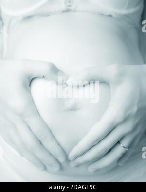 Femme enceinte avec les mains formant le cœur Banque D'Images