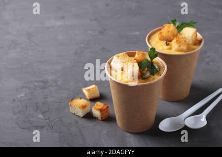 Soupe épaisse à la crème de citrouille végétalienne avec graines et croûtons dans des tasses jetables de papier artisanal. Soupe à emporter. Une alimentation saine. Emporter la nourriture. Banque D'Images