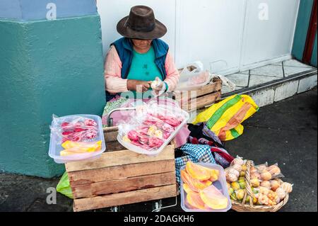 Femme ethnique âgée en chapeau assis et vendant des fruits dans la rue de la ville, Lima, Pérou Banque D'Images