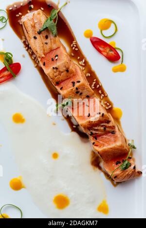 saumon grillé avec sauce sur une assiette blanche Banque D'Images