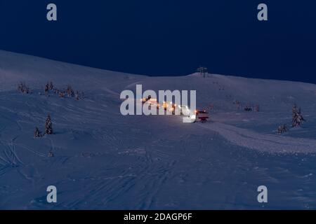 Snow groomers (machines de ratrack de chat de neige) lors d'une excursion nocturne avant l'aube jusqu'au sommet de montagne d'hiver avec des freeriders snowboarders. Dragobrat, Ukraine. Péop Banque D'Images