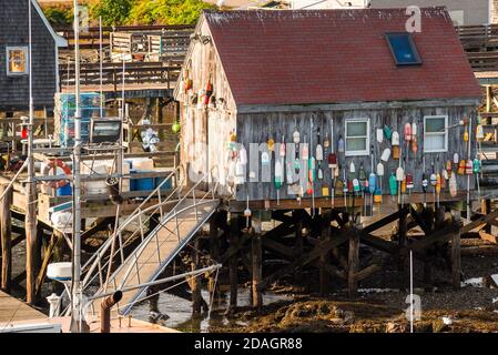 Cabane de pêche traditionnelle en bois avec bouées colorées suspendues au mur extérieur à l'extrémité de la jetée dans un port au coucher du soleil Banque D'Images