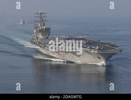 Le porte-avions USS Nimitz de la Marine américaine navigue en formation avec le destroyer de missiles guidés de la classe Arleigh Burke, le destroyer de missiles guidés USS John Paul Jones, au centre, et le croiseur de missiles guidés USS Princeton lors d'un transit du détroit d'Hormuz le 9 novembre 2020 dans le golfe Persique. Banque D'Images