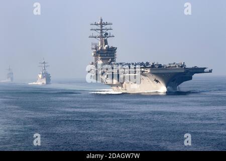 Le porte-avions USS Nimitz de la Marine américaine navigue en formation avec le destroyer de missiles guidés de la classe Arleigh Burke, le destroyer de missiles guidés USS John Paul Jones, au centre, et le croiseur de missiles guidés USS Princeton lors d'un transit du détroit d'Hormuz le 9 novembre 2020 dans le golfe Persique. Banque D'Images