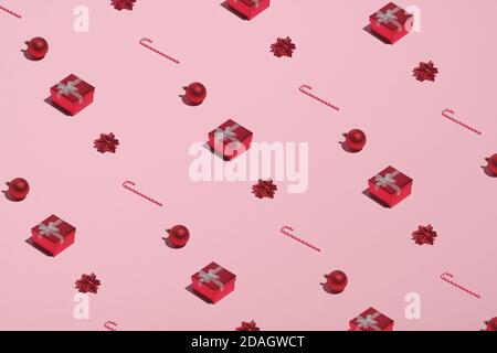 Motif de Noël fait de boîtes-cadeaux rouges, Cannes de bonbons, décorations, boules sur fond rose. Noël nouvel an, vacances d'hiver concept. Banque D'Images