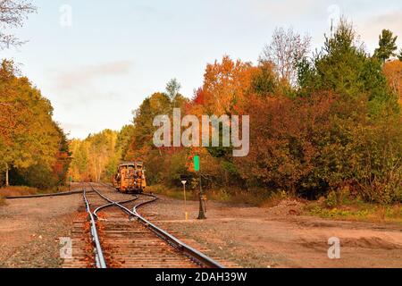 Trout Lake, Michigan, États-Unis. Entretien de matériel de voie assis sur une voie d'évitement parmi les couleurs d'un automne émergent. Banque D'Images