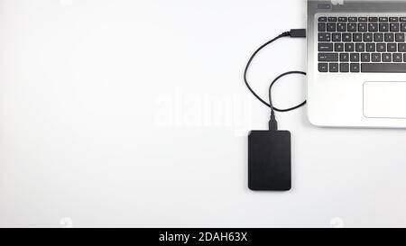 Disque dur externe connecté à l'ordinateur portable sur une surface blanche. Concept pour le bureau, les affaires, l'éducation et la présentation Banque D'Images