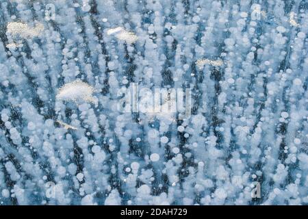 Belle glace bleue transparente avec bulles de méthane blanches congelées. Structure hivernale du lac Baikal gelé. Vue de dessus. Arrière-plan naturel. Espace de copie. Banque D'Images