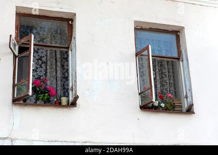 Ancienne maison rustique avec fenêtres ouvertes et fleurs en fleur chaude journée d'été Banque D'Images