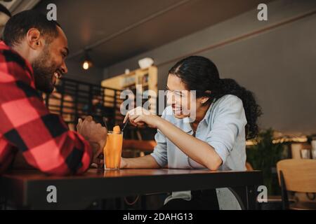 Femme assise au café avec son petit ami et souriante. Couple à la date au café-restaurant. Banque D'Images