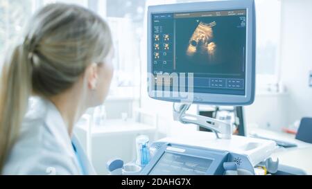 À l'hôpital, obstétricien regardant l'écran d'ordinateur à la sonde pour l'échographie examen de l'échogramme examen du ventre de la femme enceinte Banque D'Images