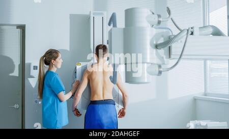 À l'hôpital, un homme debout face au mur tandis que le technicien médical règle la machine à rayons X pour l'acquisition. Acquisition pour les fractures, les membres cassés Banque D'Images