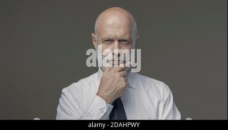 Portrait d'un homme d'affaires d'âge moyen confiant pensant main sur le menton, stratégies d'affaires et concept de leadership Banque D'Images
