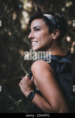 Gros plan portrait d'une belle femme dans la forêt tout en randonnée et en appréciant la nature en portant un sac à dos dans le bois Banque D'Images