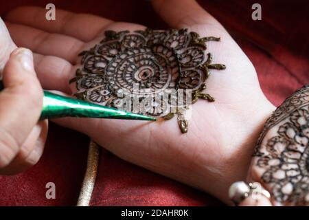 Gros plan sur le tatouage au henné mehendi appliqué dans un motif complexe sur la main d'une femme lumière naturelle douce et rouge Banque D'Images