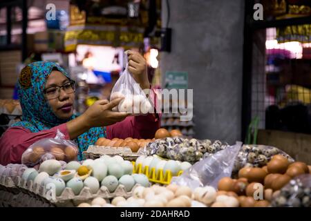 Denpasar, Bali, Indonésie - 8 AOÛT 2019 : femme préparant des œufs à vendre sur le marché couvert Banque D'Images