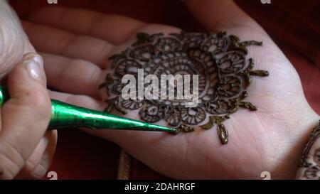 Gros plan sur le tatouage au henné mehendi appliqué dans un motif complexe sur la main d'une femme lumière naturelle douce et rouge Banque D'Images
