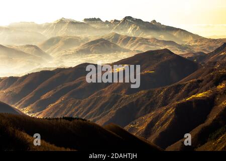 Vue panoramique sur la montagne italienne contre les bois pendant le coucher de soleil brumeux en hiver, Lucca, Toscane, Italie Banque D'Images