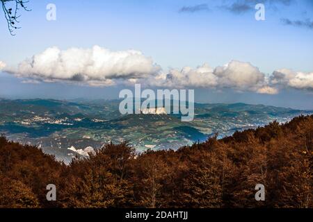 Vue panoramique de l'Eremo Pietra di Bismantova contre les bois de couleur automnale et derrière un ciel nuageux, Monte Cusna, Reggio Emilia, Italie Banque D'Images