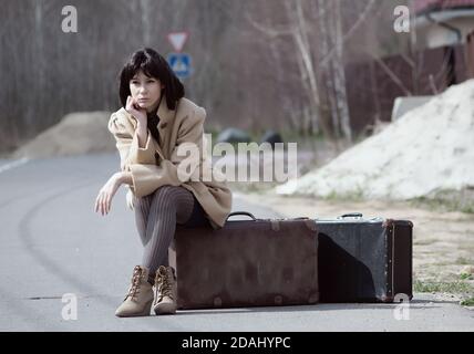 brunette femme en attente de s'asseoir sur une valise Banque D'Images