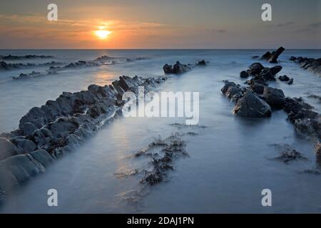 Vue sur les crêtes rocheuses au coucher du soleil à l'embouchure de Welcombe Plage sur la frontière du Devon et de Cornwall Banque D'Images