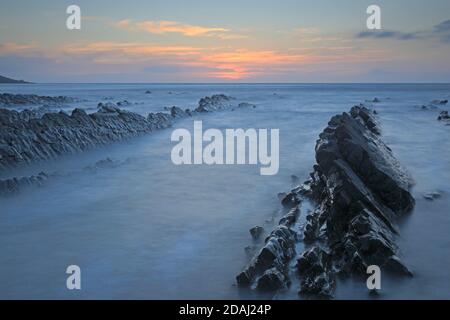 Vue sur les crêtes rocheuses au coucher du soleil à l'embouchure de Welcombe Plage sur la frontière du Devon et de Cornwall Banque D'Images