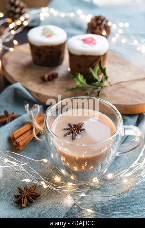 Thé au masala et gâteaux sucrés sur une table avec décoration de Noël. Le Masala chai est une boisson de thé indien faite en faisant bouillir le thé noir dans le lait et l'eau avec un mélange d'herbes aromatiques et d'épices Banque D'Images