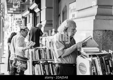 New York, Etats-Unis - 16 septembre 2017 : image en noir et blanc de Strand Book Store à Manhattan. Un vieil homme aux cheveux gris choisit un livre à acheter Banque D'Images