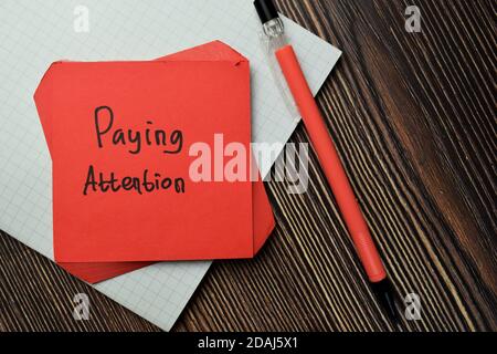 Faire attention écrire sur le billet collant isolé sur la table en bois. Concept financier Banque D'Images