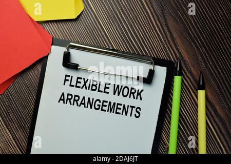 Les Arrangements de travail flexibles écrivent sur une paperasse isolée sur fond de bois. Banque D'Images