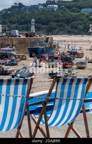 Transats en face des bateaux à marée basse, port de St Ives, Cornwall, Royaume-Uni Banque D'Images