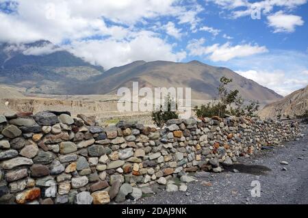 Pierre la protection traditionnelle contre les vents contre la toile de fond des montagnes himalayenne a lieu dans les sommets supérieurs de la Mustang. Randonnée en t Banque D'Images