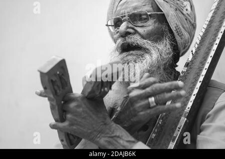 Musicien de rue âgé chantant des chansons et de la musique traditionnelles pour le divertissement touristique le 28 octobre 2019 à Udaipur, Rajasthan, Inde. Banque D'Images