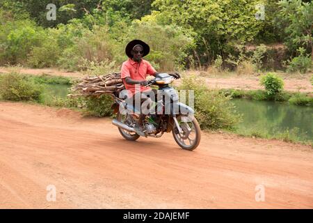 Selingue, Mali, 26 avril 2015; UN agriculteur conduit à vélo à travers la canelle principale d'irrigation. Banque D'Images